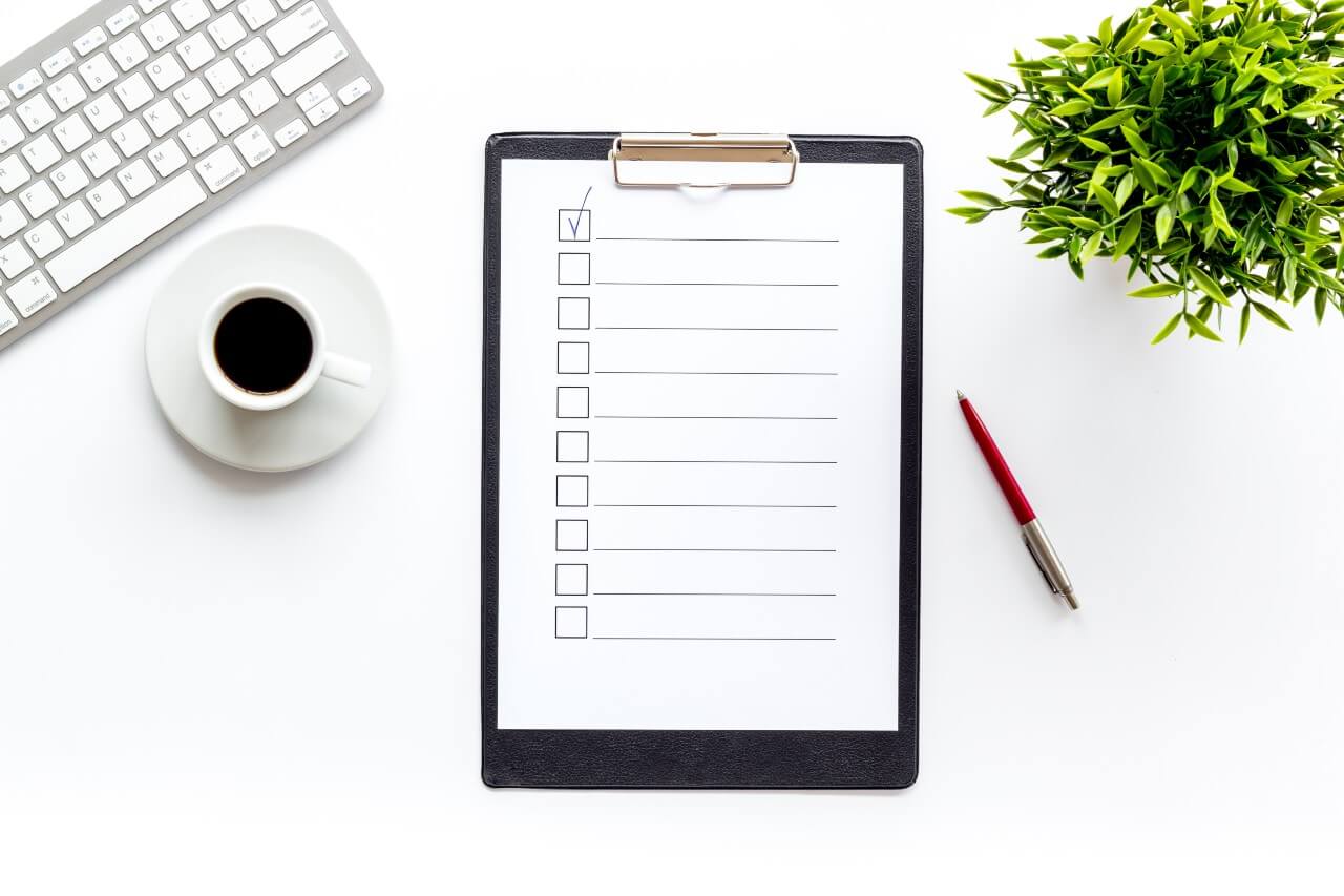 Paper checklist on a clipboard next to office supplies