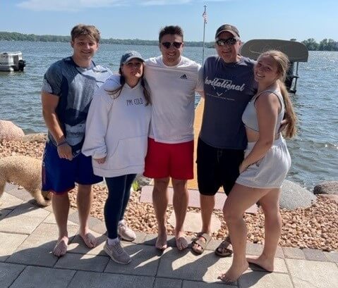 Twin Cities Pain Clinic patient Jayson Rogers posing with his family in front of a lake on a sunny summer day