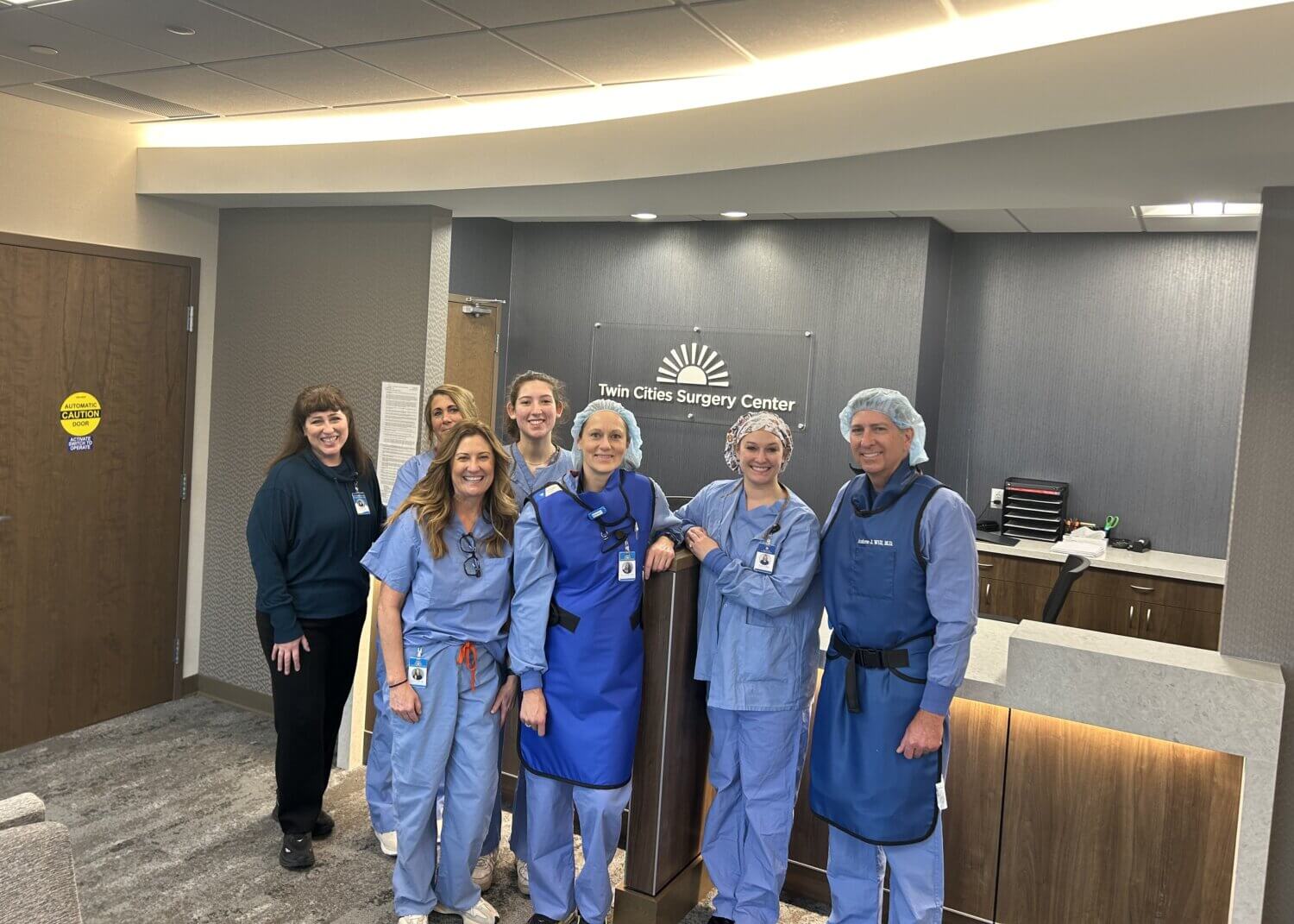 The Twin Cities Surgery Center team posing in front of the reception desk at the Maplewood, MN location