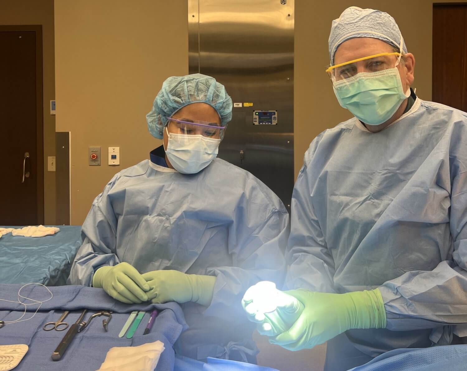 Dr. Andrew Will in full surgical garb holding an Inceptiv spinal cord stimulator battery