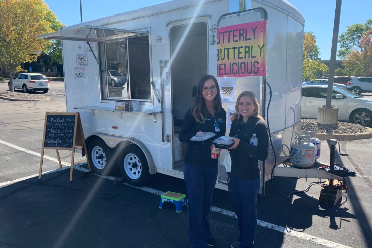 Two Twin Cities Pain Clinic employees holding food in front of a food truck