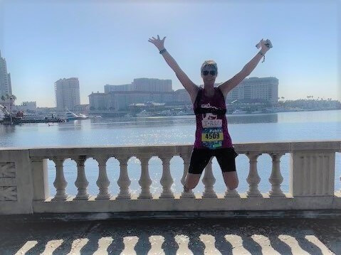 Radiofrequency Ablation Patient Lisa Brecht jumping for joy on a bridge over a bay with a city in the background