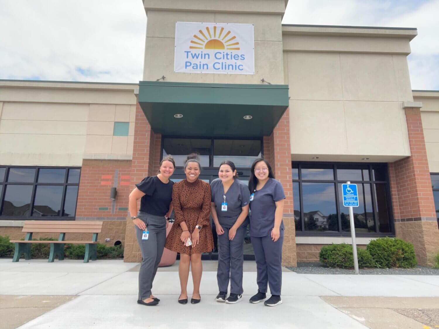 Four staff members standing in front of the main entrance of Twin Cities Pain Clinic in Maplewood, MN