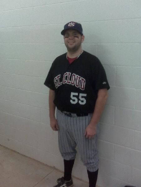 Troy Thielen standing in front of a white brick wall wearing St. Cloud baseball uniform