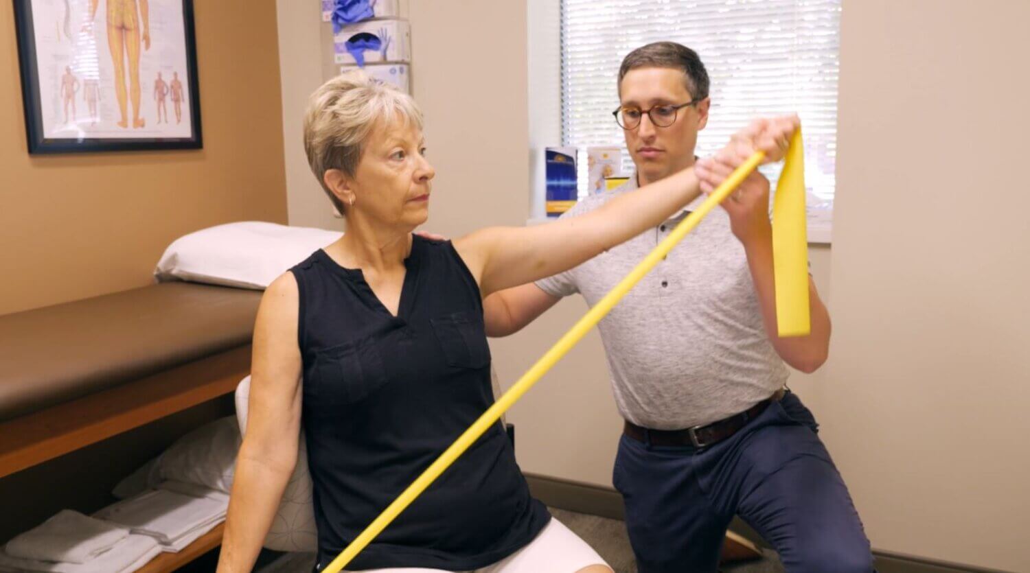 Physical therapist helping a patient perform exercises with an exercise band