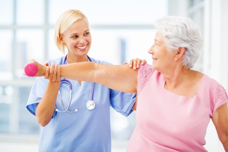 Young female physical therapist performing physical therapy on a senior female