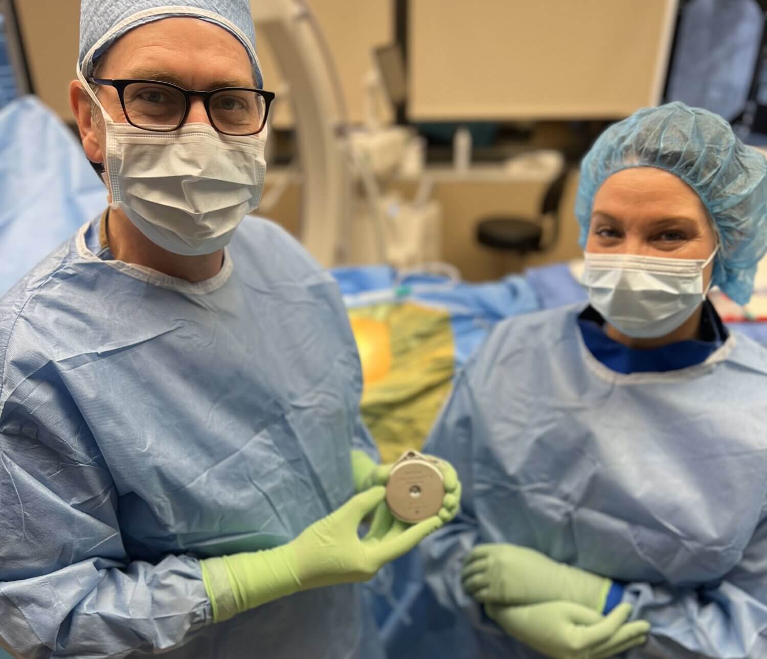 Close up image of Dr. Andrew Will and surgery nurse in surgical garments holding the new SynchroMed™ III intrathecal pump system by Medtronic